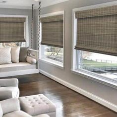 a living room filled with furniture and windows covered in roman blind shades on top of them