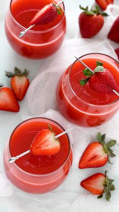 two glasses filled with red liquid and strawberries