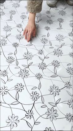 someone's hand is on the floor with black and white flower designs painted on it