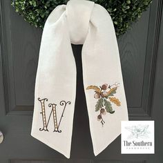 a white scarf hanging on a door with the initials w and m embroidered on it