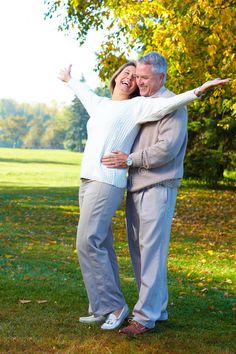 an older couple is hugging in the park