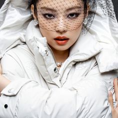 a woman in a white jacket with a veil on her head and an orange lip