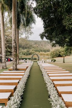 an outdoor ceremony setup with white flowers and greenery on the aisle, surrounded by palm trees