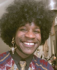 a man with an afro smiles for the camera