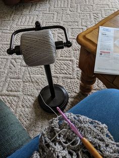 a knitting machine sitting on the floor next to a person's legs