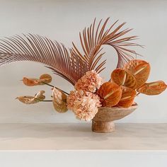 an arrangement of flowers in a vase on a shelf