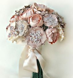 the bridal bouquet is adorned with pink flowers and white satin ribbons, which are attached to an ivory - colored ribbon