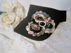 I designed this adorable black visor with beautiful matching variegated shabby flowers. I added a beautiful black and rhinestone center accent. Visor has velcro back I also have more colors that I will be listing as well. See more hats and visor here: https://www.etsy.com/shop/theraggedyrose?ref=seller-platform-mcnav&section_id=10557807 Custom orders alway welcome. Thanks for visiting my shop. Adjustable Black Visor With Curved Brim, Black Adjustable Visor With Curved Brim, Black Visor With Curved Brim, One Size Fits Most, Black Spring Headband Hats, Black Headband Hat For Spring, Adjustable Black Brimmed Mini Hat, Adjustable Brimmed Black Mini Hats, Black Mini Hat Headband For Spring, Vintage Black Mini Hat For Spring