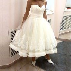 a woman in a white dress standing next to a radiator