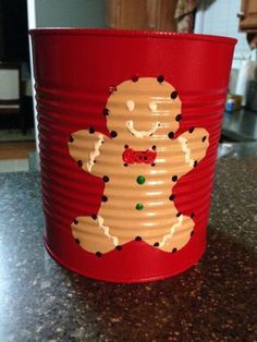 a red tin can with a gingerbread man on it sitting on a counter top