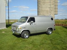 a silver van parked in front of a silo