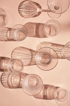 several wine glasses are lined up on a table with the shadows from one glass in front of them