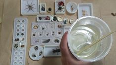 a person holding a plastic cup filled with white liquid and lots of other items on the table