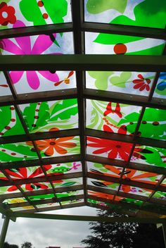 the ceiling is decorated with colorful flowers and leaves on it's glass coverings