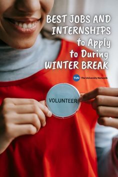 a woman in an orange apron holding up a volunteer badge