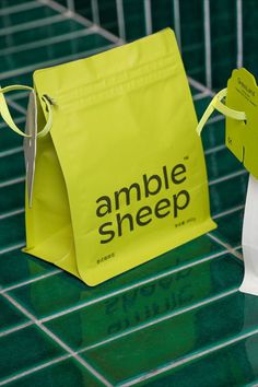 a green and white bag sitting on top of a table next to a yellow paper bag