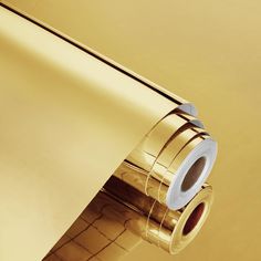 a roll of gold colored paper on top of a shiny metallic surface with the end rolled up