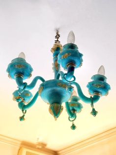 a blue chandelier hanging from the ceiling in a room with white walls and ceilings