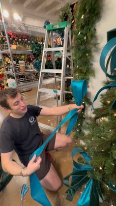 a young man is sitting on the floor with blue ribbon around his ankles and holding onto a ladder