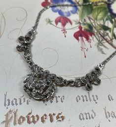 Vintage 1950's -1960's silver tone and marcasite necklace. An original vintage silver tone necklace set with sparkling marcasites. A very pretty, floral design. The chain is a fancy flat link design with a spring ring fastener.  What is marcasite? - Marcasite is a faceted grey stone called pyrite. All the stones are present but as a preloved piece , will show slight signs of wear relative to its age.  Approximate measurements  Length 15.5  inches / 39.5 cm Centre section 3 inches / 7.5 cm Vintage and preowned jewellery is another way to reduce your carbon footprint.  Postage will be combined for purchases made in the same transaction. The necklace will be gift boxed. Vintage Silver Necklace With Jewels, Vintage Sterling Silver Necklace With Jewels, Silver Flower Pendant Costume Jewelry, Silver Jewelry With Jewels For Vintage Events, Ornate Silver Necklaces For Vintage Events, Silver Jeweled Jewelry For Vintage Events, Silver Round Vintage Necklace, Silver Pendant Necklace For Vintage Events, Victorian Silver Necklace With 17 Jewels