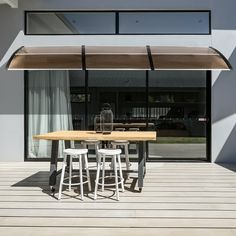 a wooden table sitting on top of a wooden floor next to a tall white building