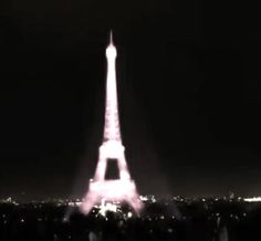 the eiffel tower is lit up at night with bright lights in the background