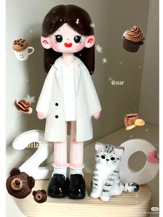 a figurine of a girl with cats and cupcakes in the background