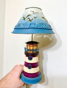 a hand holding a lamp that is shaped like a lighthouse