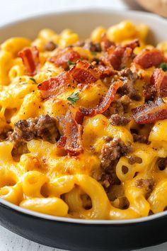 a bowl full of macaroni and cheese with bacon on top, sitting on a table