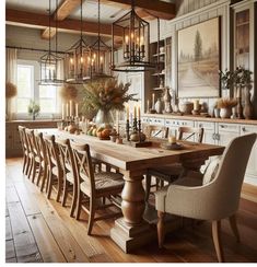 a dining room table with chairs and lights hanging from it's ceiling, surrounded by white cabinets