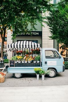 a blue truck parked in front of a building with flowers on it's side