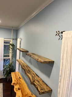 a wooden bench sitting in the middle of a room next to a window with curtains