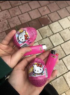 a person holding two hello kitty erasers and a pink pen in their left hand