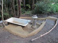 a bathtub sitting on top of a cement slab in the middle of a forest