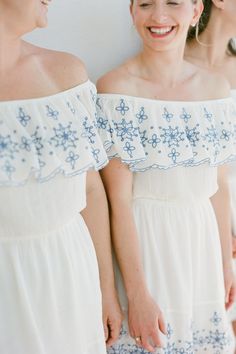 three women in white dresses are smiling and laughing