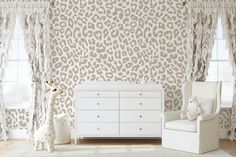 an animal print wallpaper in a child's room with a white dresser and chair