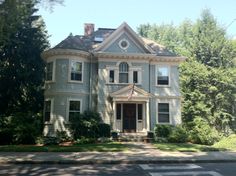 a large blue house sitting on the side of a road in front of some trees