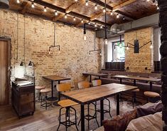 an old brick restaurant with wooden tables and bar stools, exposed ceiling lights and wood flooring