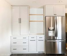 a kitchen with white cabinets and stainless steel refrigerator