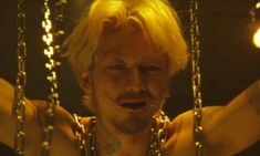 a man with blonde hair holding onto chains