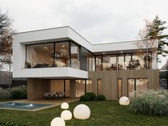 a modern house with large glass windows and lots of greenery in the front yard