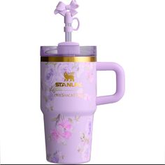 the tumbler cup has a handle and is decorated with pink flowers on purple background