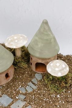 three clay houses sitting on top of a patch of dirt next to a stone walkway