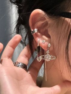 a close up of a person wearing some kind of ear piercings and holding something in their hand