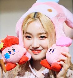 a woman holding two stuffed animals in front of her face and smiling at the camera