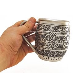 a person is holding a cup with a spoon in it and writing on the side