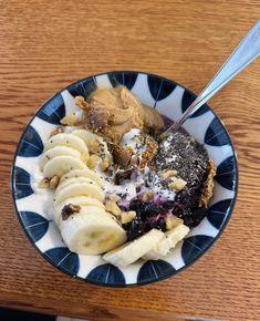 a blue and white plate topped with banana slices and other foods on top of a wooden table