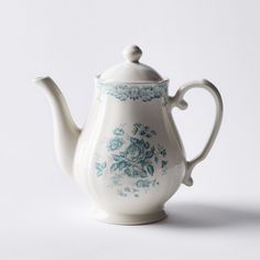 a white tea pot with blue floral designs on the side and a lid is sitting in front of a white background