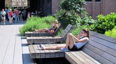 people are sitting on benches in the middle of an open area with plants and flowers