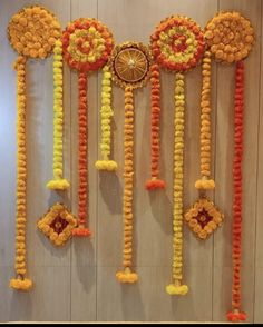 an arrangement of orange and yellow flowers hanging from the ceiling in front of a wall